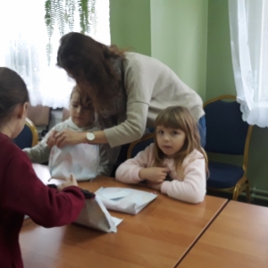 Dzieci szyją śniadaniówki podczas ferii z biblioteką.